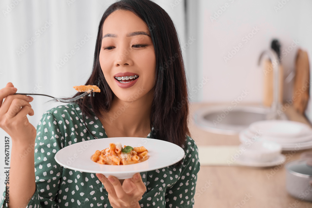 Young Asian woman eating tasty pasta in kitchen, closeup Young Asian woman eating tasty pasta in kitchen, closeup