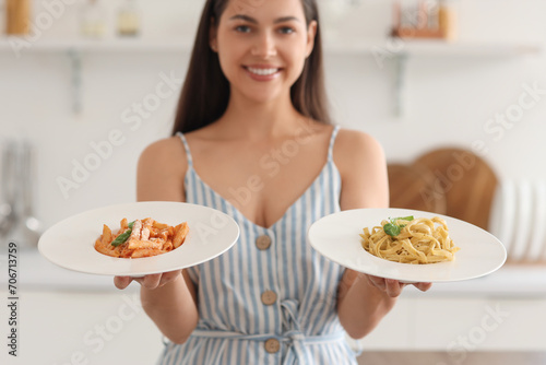 Young woman with plates of tasty pasta in kitchen  closeup