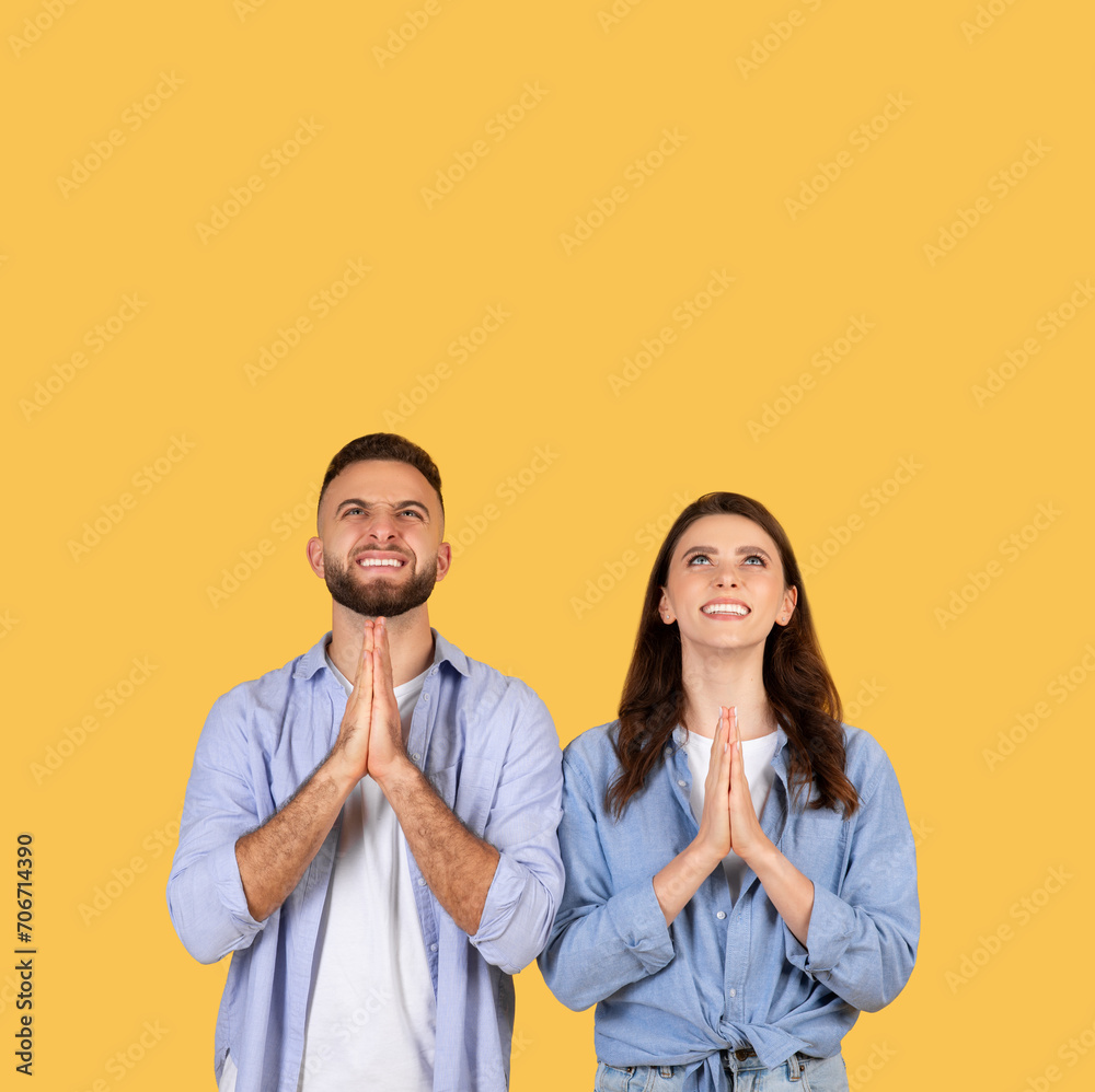 Hopeful couple with hands in prayer position, looking up at copy space Hopeful couple with hands in prayer position, looking up at copy space