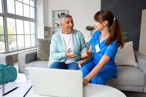 Senior woman with caregiver using laptop at home