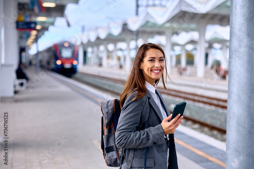 Young happy woman at train station looking at camera.