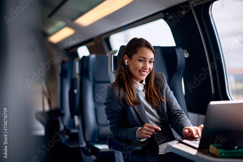 Smiling female entrepreneur surfing the net on laptop while traveling by train. photo