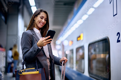 Happy woman texting on smart phone at train station. photo