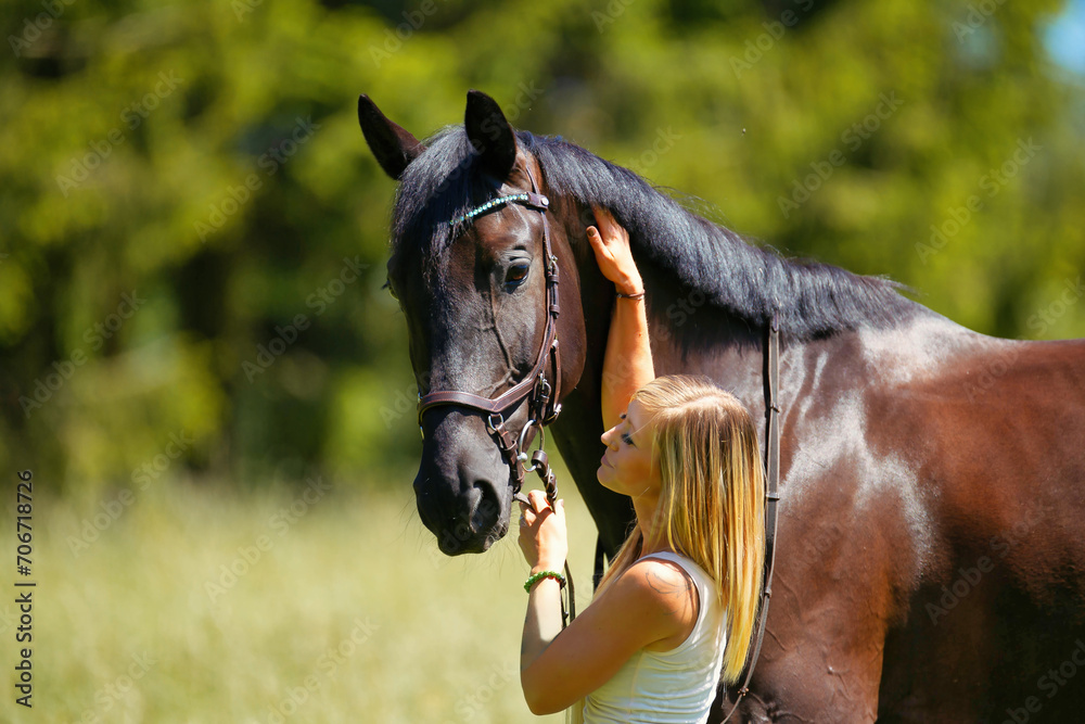 Obraz premium Woman young blonde long hair on a meadow in summer with horse.