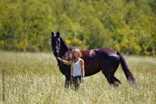Woman young blonde long hair on a meadow in summer with horse.