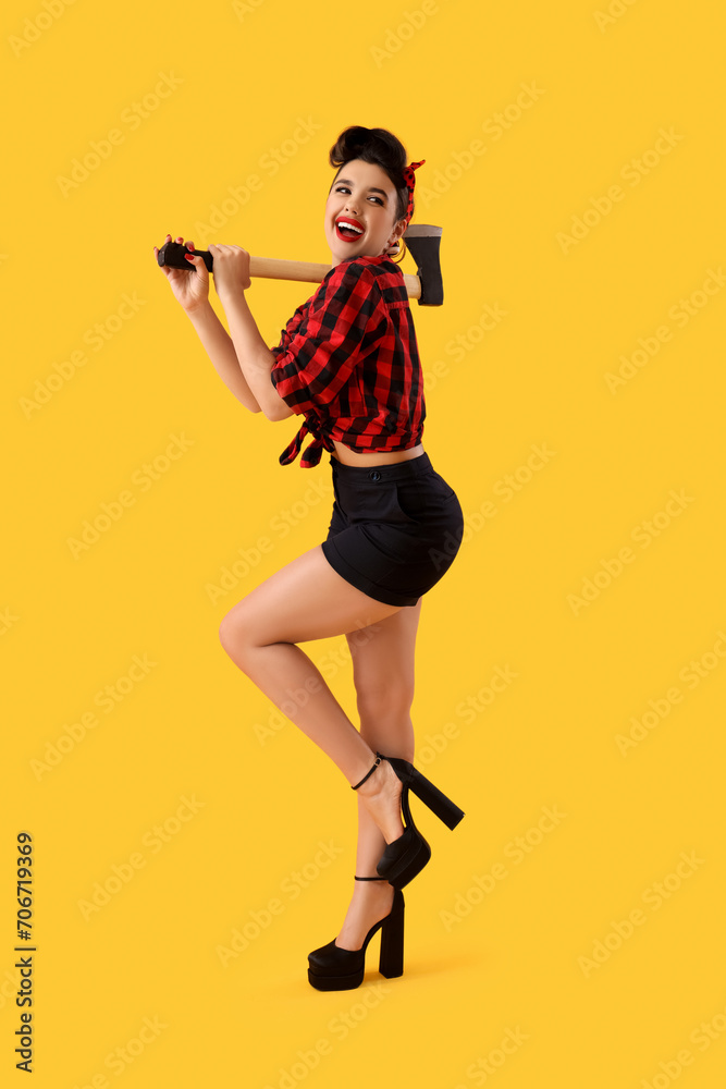 Young pin-up woman with axe on yellow background Young pin-up woman with axe on yellow background