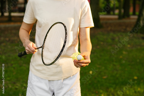 A young woman in sportswear is going to hit a shuttlecock with a racket while playing badminton outdoors. The concept of leisure and spending time in fresh air, sports © Daryna 