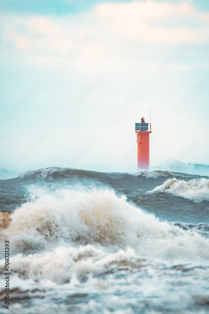 Lighthouse on the sea during Stormy weather in Riga, Latvia. Huge waves crashing down the coast