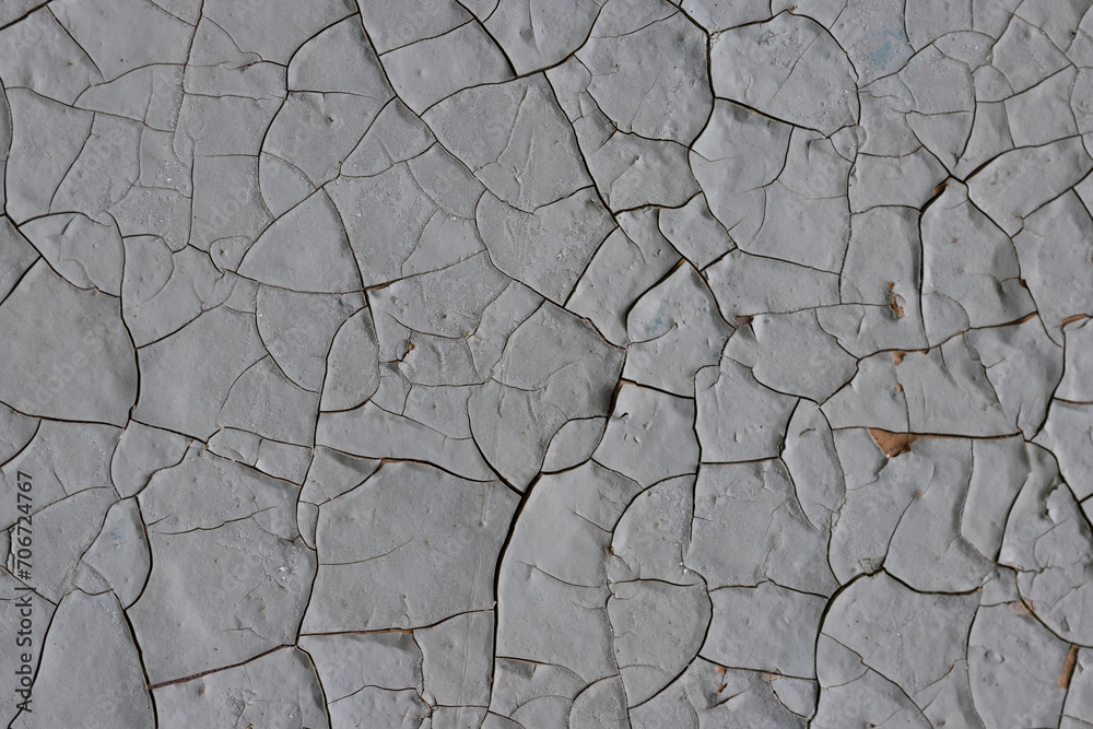 Peeling paint on the wall. Old concrete wall with cracked flaking paint. Weathered rough painted surface with patterns of cracks and peeling. Grunge texture for background and design. High resolution.