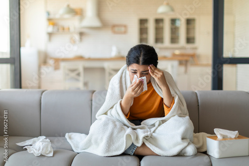 Ill indian woman blowing her nose with tissue at home photo