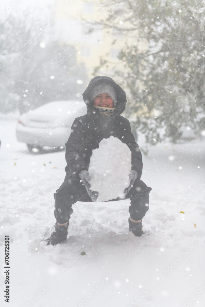 a girl is playing with snow on the street, it is snowing, a blizzard and frost on a winter day a girl is playing with snow on the street, it is snowing, a blizzard and frost on a winter day