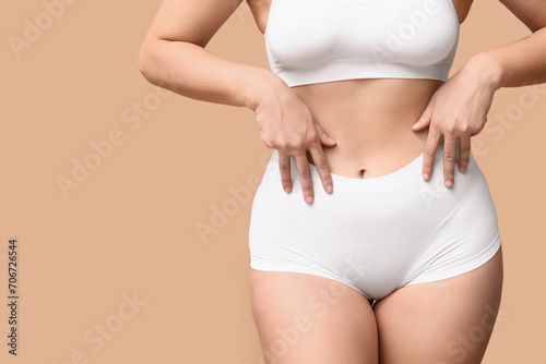 Body positive woman in underwear on beige background, closeup