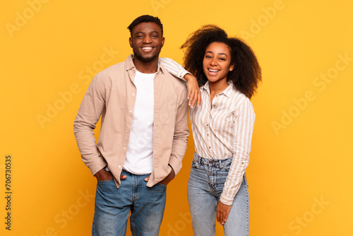 Smiling black couple standing together against yellow background