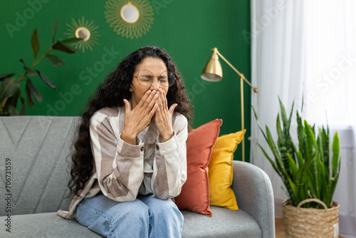 Young woman yawns bored sitting at home on sofa in living room. photo