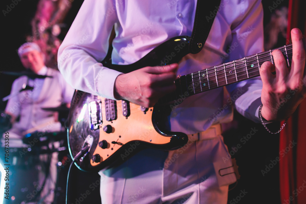 Concert view of an electric guitar player with vocalist and rock band performing in a club, male musician guitarist on stage with audience in a crowded concert hall arena - obrazy, fototapety, plakaty 
