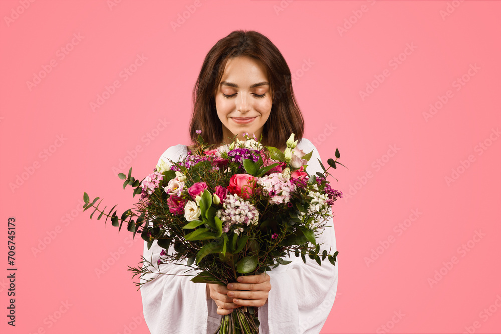 Contented young woman in a white blouse, eyes closed, serenely smelling a large Contented young woman in a white blouse, eyes closed, serenely smelling a large