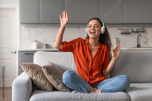 Εκτύπωση καμβά Joyful woman with headphones singing at home on sofa