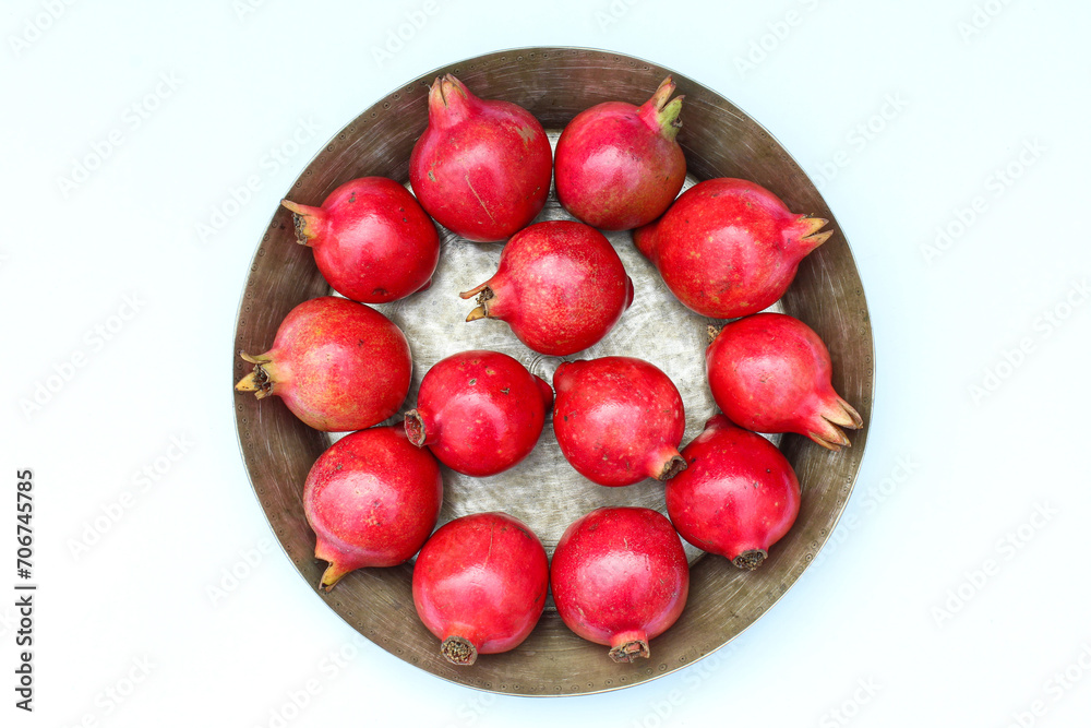 Pomegranate fruits in a plate on white background top view Pomegranate fruits in a plate on white background top view