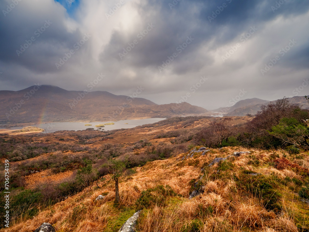 Rainbow over magnificent nature scene with valley in a mountains and dark dramatic sky. Ladies view, Killarney, Ireland, ring of Kerry route. Magnificent Irish nature and popular tourist area.
