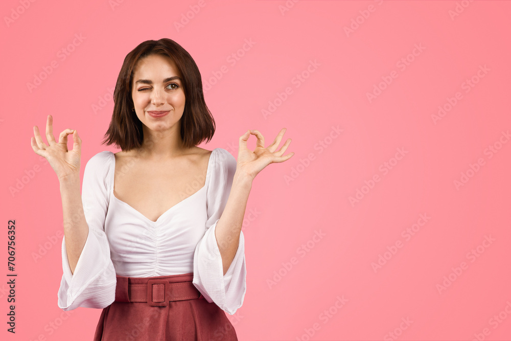 Confident young woman winking and gesturing 'perfect' with her fingers Confident young woman winking and gesturing 'perfect' with her fingers