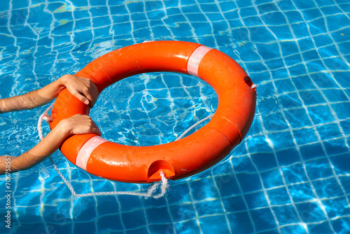 Lifeguard girl training with a life preserver swimming in the pool