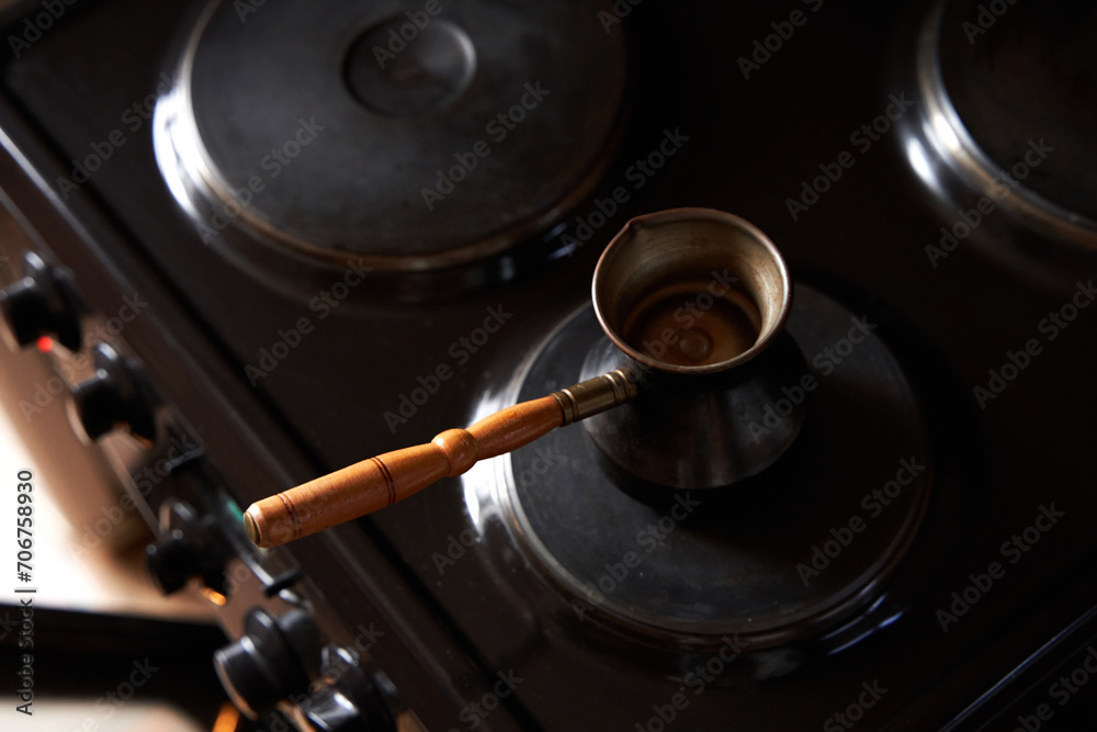 A man preparing black coffee on electric stove. Brew coffee in a Turkish coffee pot A man preparing black coffee on electric stove. Brew coffee in a Turkish coffee pot