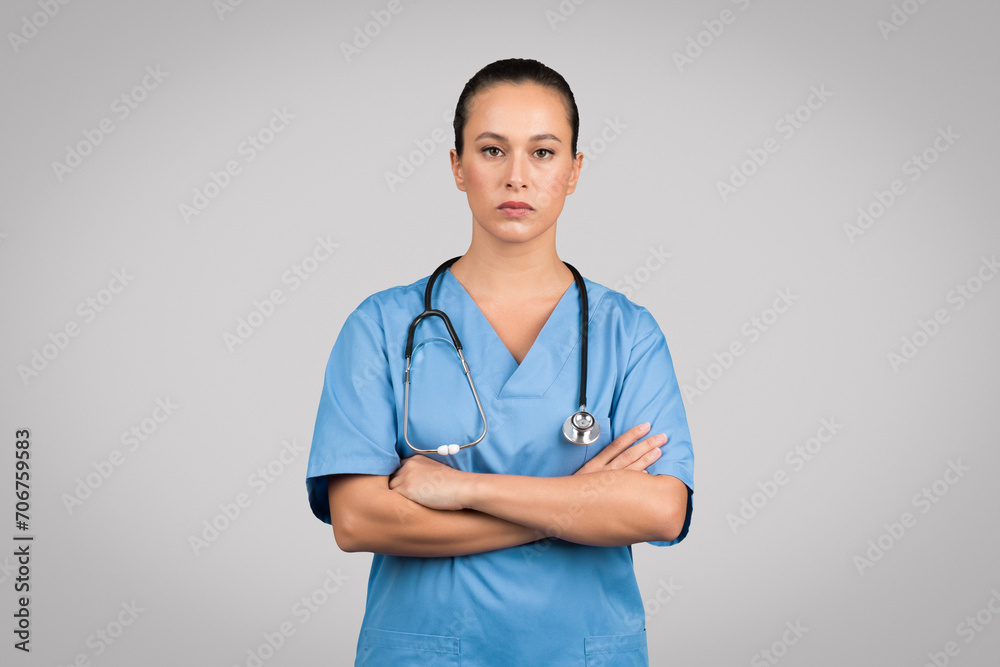 Stern nurse with arms crossed in scrubs