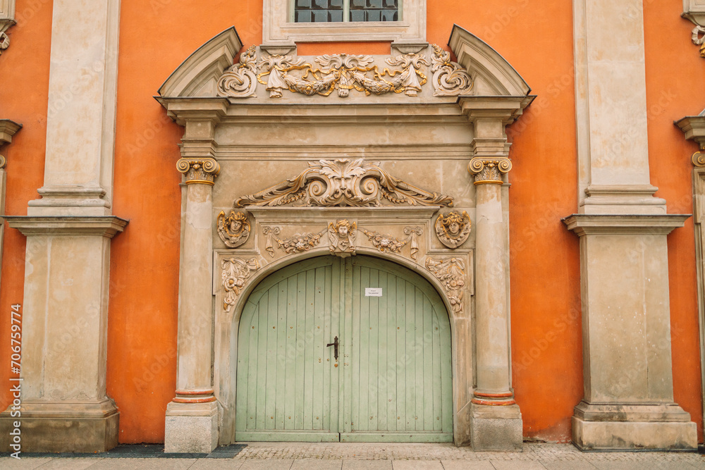 Carved wooden old green door in Gdansk.Orange wall with antique decor of columns. High quality photo