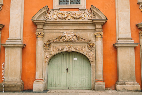Carved wooden old green door in Gdansk.Orange wall with antique decor of columns. High quality photo © Shi 