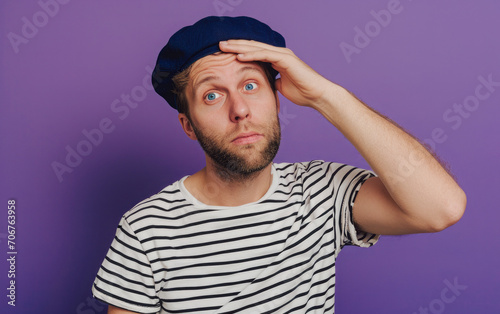 Mistake and misunderstanding, guy holding head in shock on purple background. © mimi