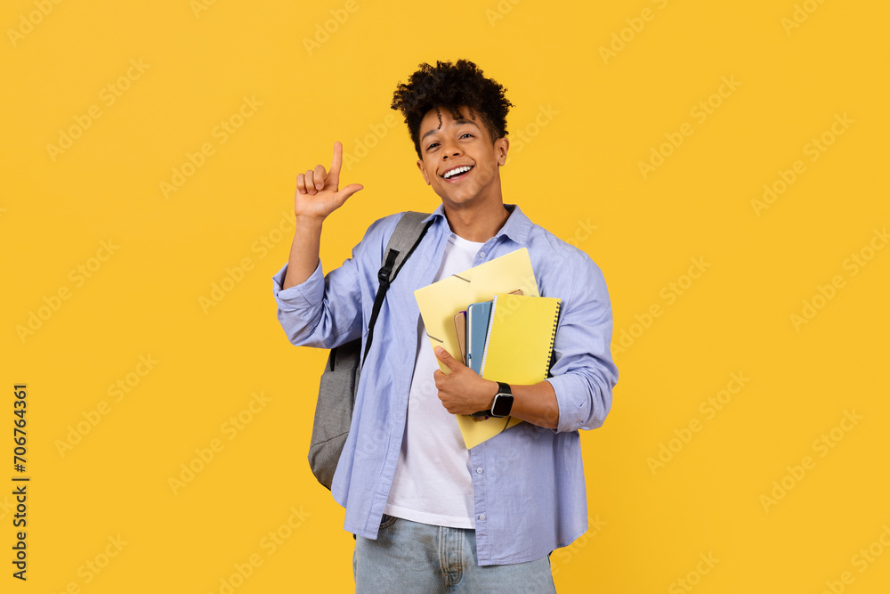 Cheerful student gesturing size with hand on yellow background Cheerful student gesturing size with hand on yellow background