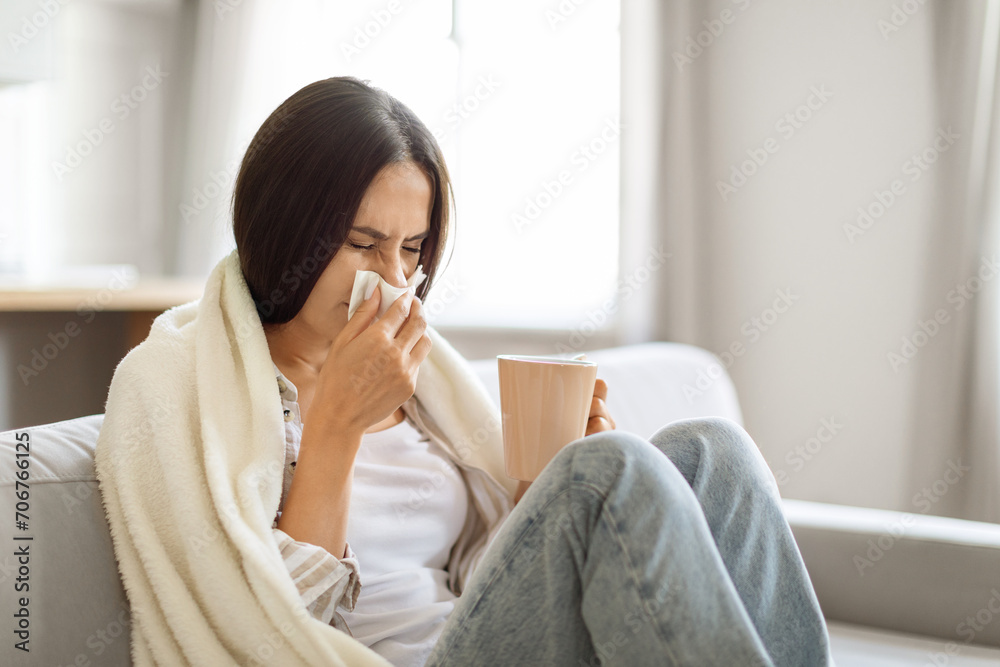 Young woman feeling sick at home, blowing her nose with tissue Young woman feeling sick at home, blowing her nose with tissue