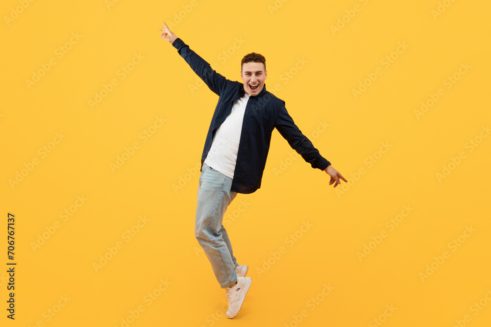Cheerful young stylish caucasian guy moving on yellow background