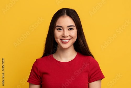 Portrait of attractive young asian woman posing on yellow background