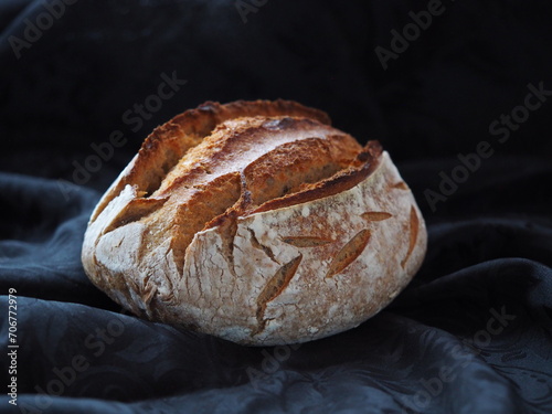 Isolated homemade sourdough loaf on black background, space for text