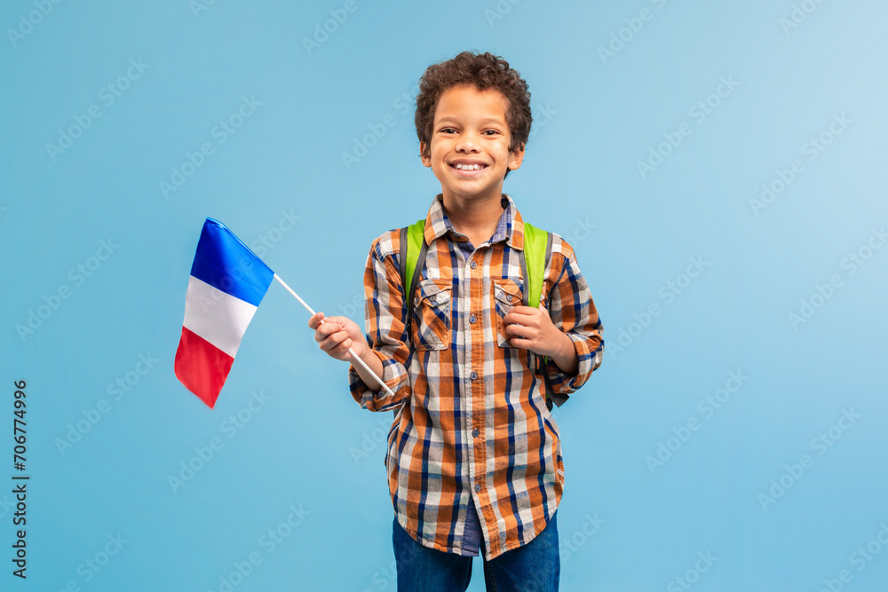 Cheerful child with French flag, plaid shirt, blue background Cheerful child with French flag, plaid shirt, blue background