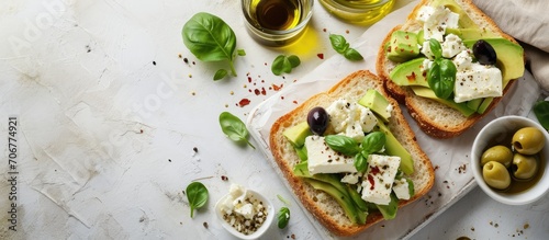 Open sandwich made of slices of sourdough bread with avocado feta cheese kalamata olives olive oil and oregano on a wooden white table close up Vegetarian food. with copy space image photo