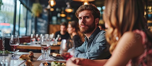 They have nothing more to say Frustrated young man looking away while sitting together with his girlfriend in restaurant. with copy space image. Place for adding text or design photo