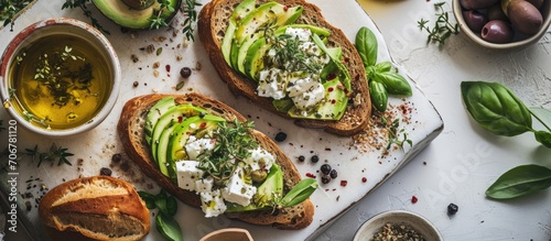 Open sandwich made of slices of sourdough bread with avocado feta cheese kalamata olives olive oil and oregano on a wooden white table close up Vegetarian food. with copy space image
