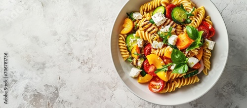 pasta salad with grilled vegetables zucchini eggplant bell pepper ant tomato and feta cheese on white bowl top view. with copy space image. Place for adding text or design