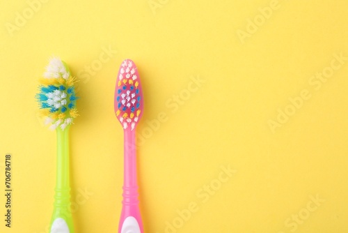 Colorful plastic toothbrushes on yellow background, flat lay. Space for text © New Africa