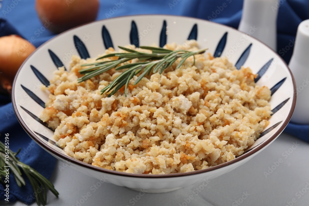 Fried ground meat in bowl and rosemary on white tiled table, closeup Fried ground meat in bowl and rosemary on white tiled table, closeup