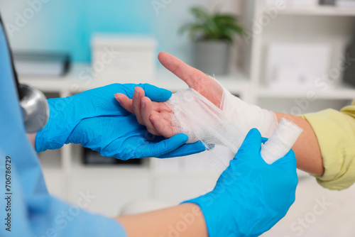 Doctor bandaging patient's burned hand in hospital, closeup