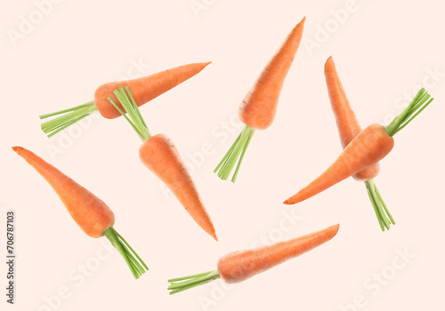 Fresh ripe carrots falling on beige background