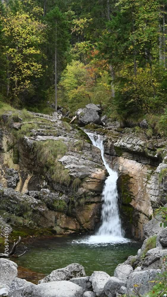 A fountain like waterfall and a pond with in autumn, colorful trees, moody atmosphere, vertical shot A fountain like waterfall and a pond with in autumn, colorful trees, moody atmosphere, vertical shot
