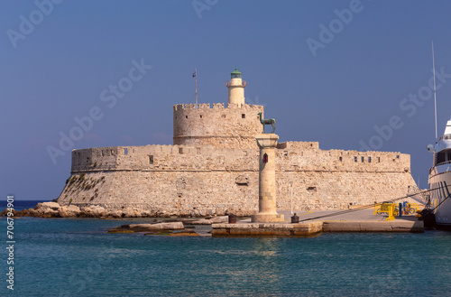Old stone lighthouse illuminated by the sun at Fort St. Nicholas in Rhodes. © pillerss