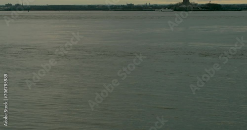 Tilt Up from Waters of New York Bay to Statue of Liberty at Sunset