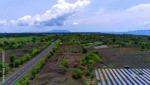 A vibrant patchwork of emerald green plantation stretches beneath a winding, asphalt road. photo