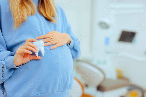 Pregnant Woman Holding a Tooth in a Dental Cabinet. Unrecognizable mother to be ready for a routine check-up at the dentist
