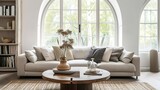 Rustic accent round coffee table near fabric sofa with many pillows against arched window. Scandinavian farmhouse style home interior design of modern living room